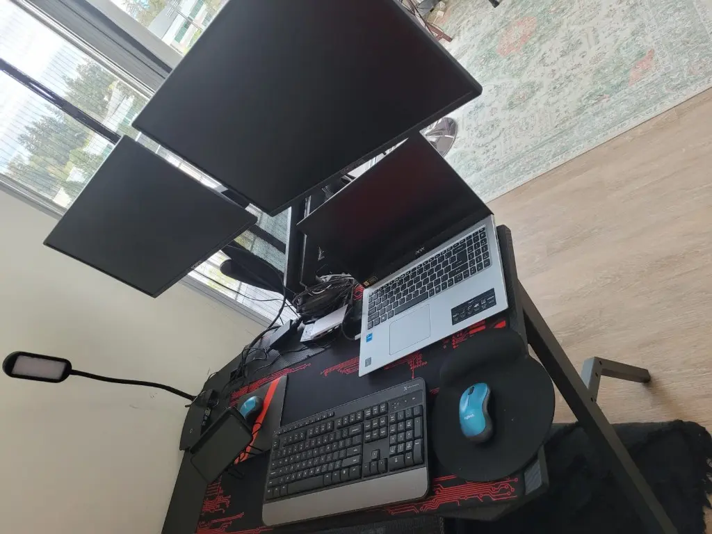 Overhead view of a desk with two monitors, a laptop, an external keyboard and a wrist rest.