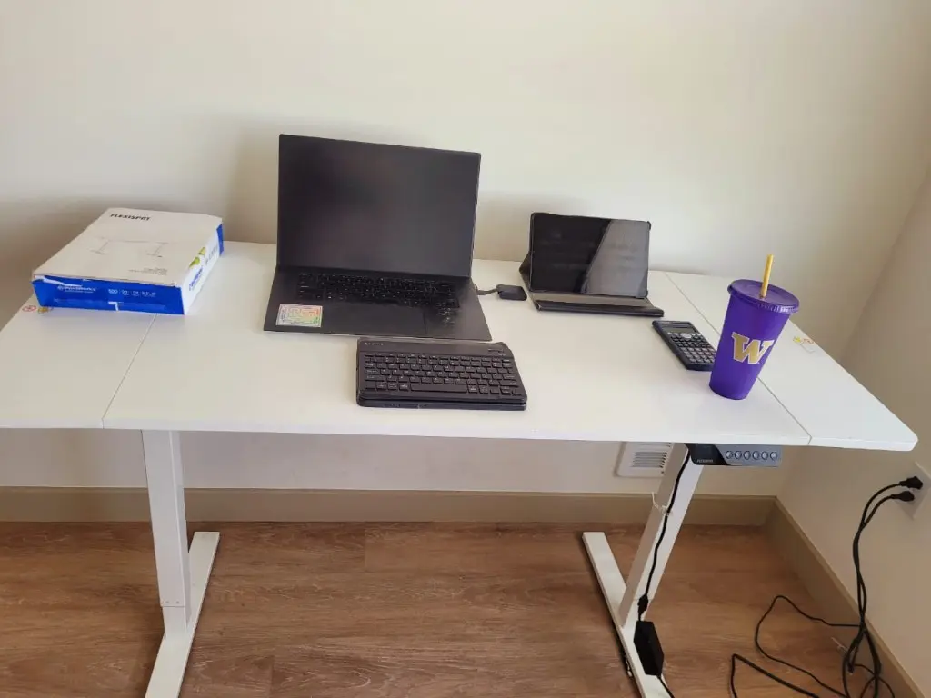 A height-adjustable desk raised to standing height, with a laptop, tablet and separate keyboard.